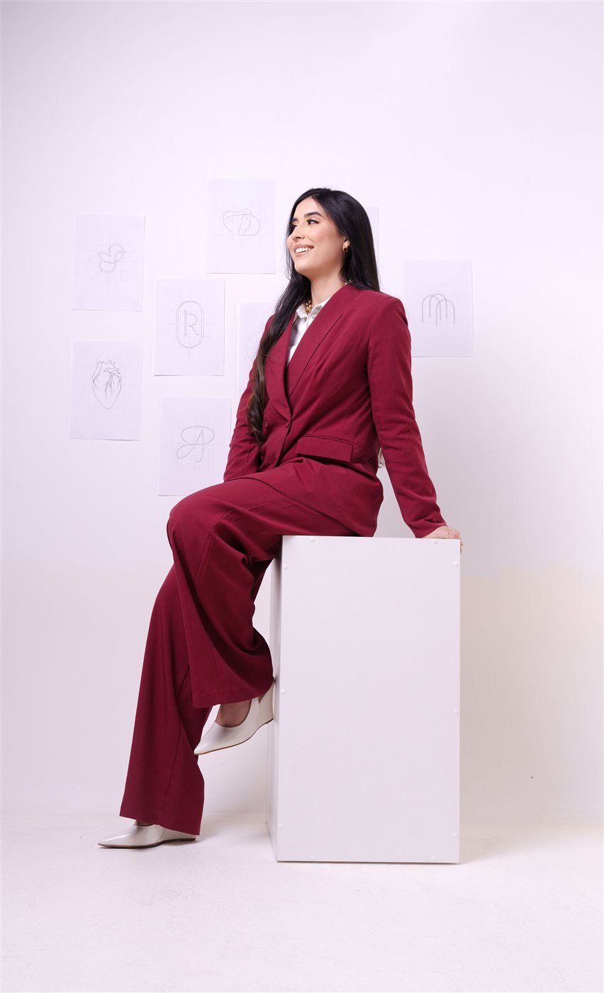 Izabela Evangelista em estúdio, sentada com referências de identidade visual ao fundo